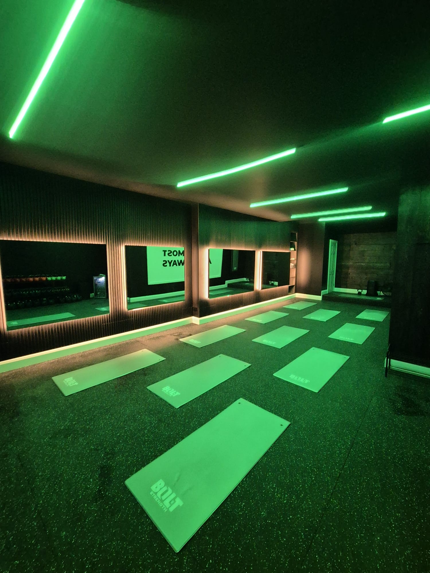 Studio interior with mats and mirrored wall under green neon lighting
