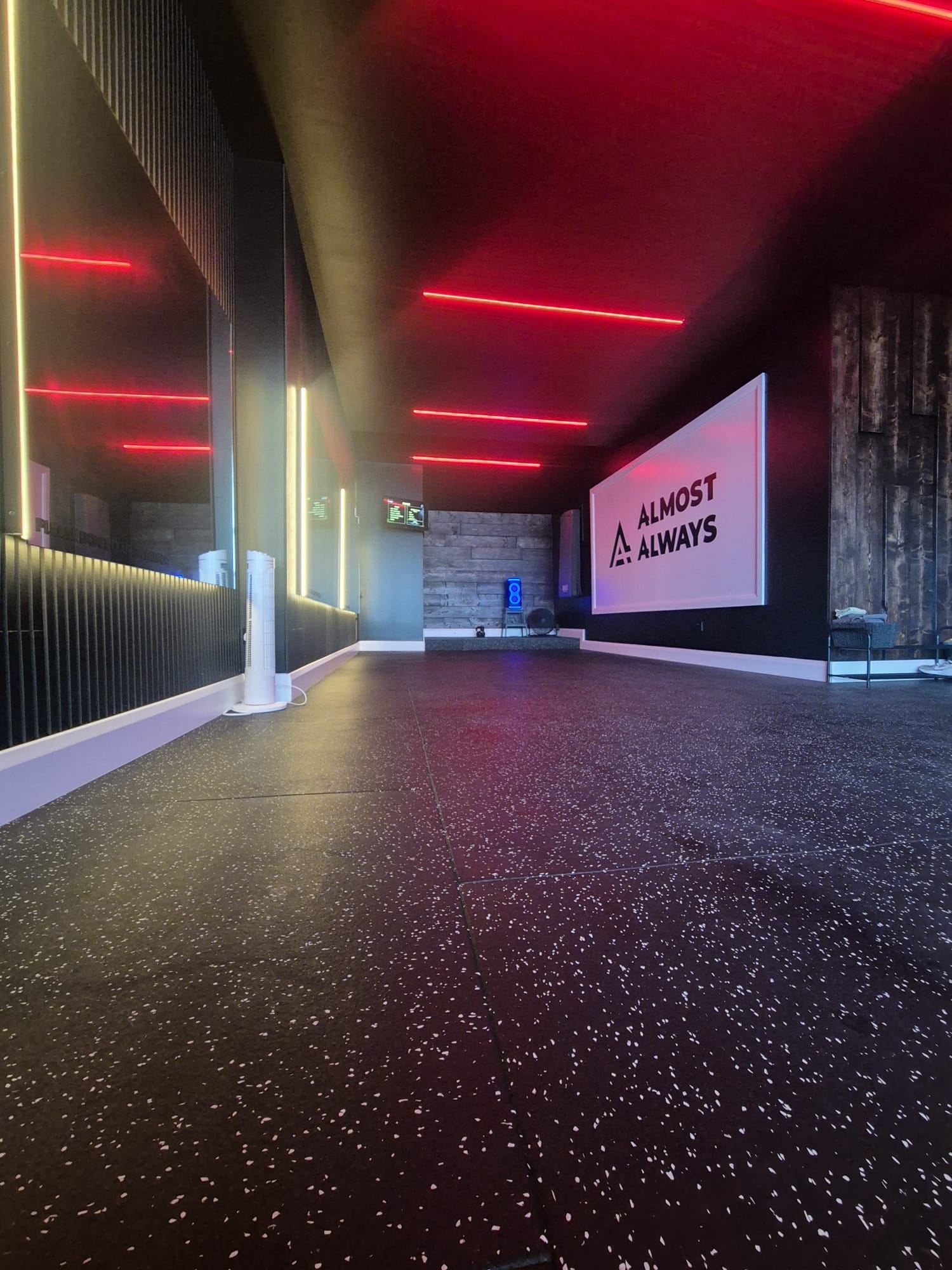 Open training floor with the Almost Always sign under red neon lighting
